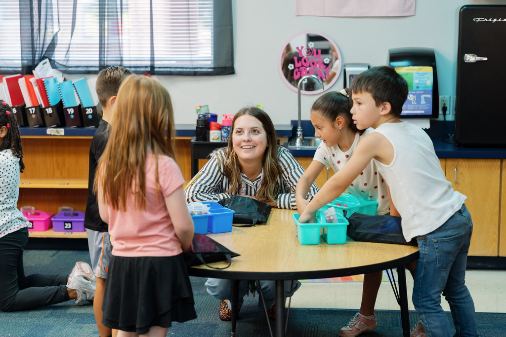 students and teacher sitting around a table talking
