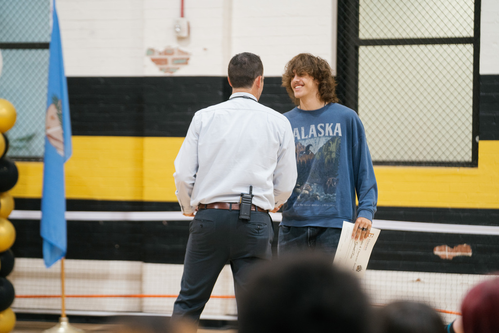 Student smiling and shaking principal's hand