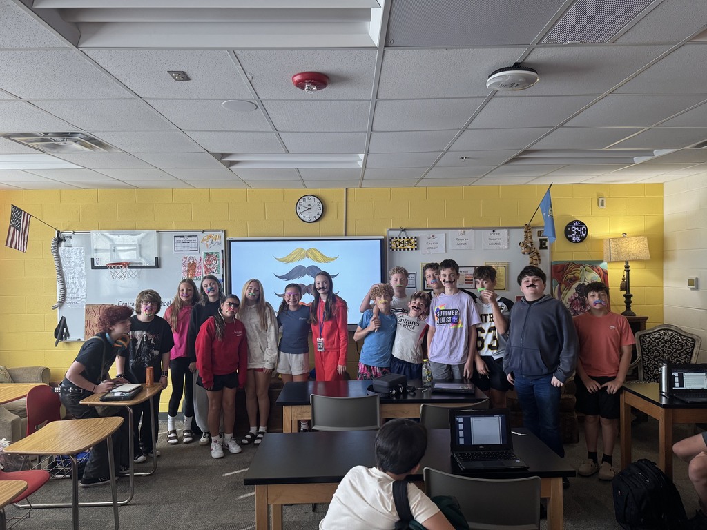 Group of students smiling for a picture wearing fake mustaches to celebrate reading "Moustache"