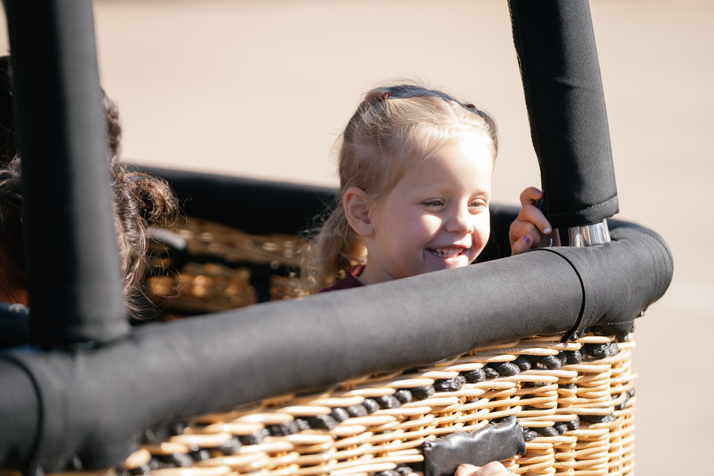student in a large basket smiling
