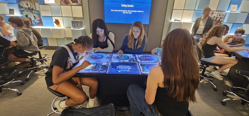 Five girls studying evidence on a touch screen computer panel table