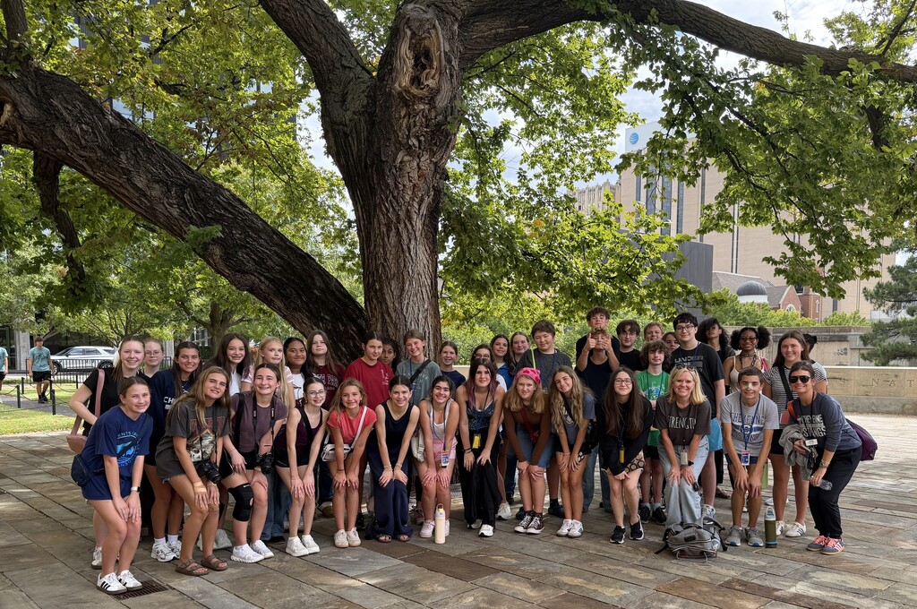 A group of students and two teachers posing in front of the Survivor Tree at the OKC memorial