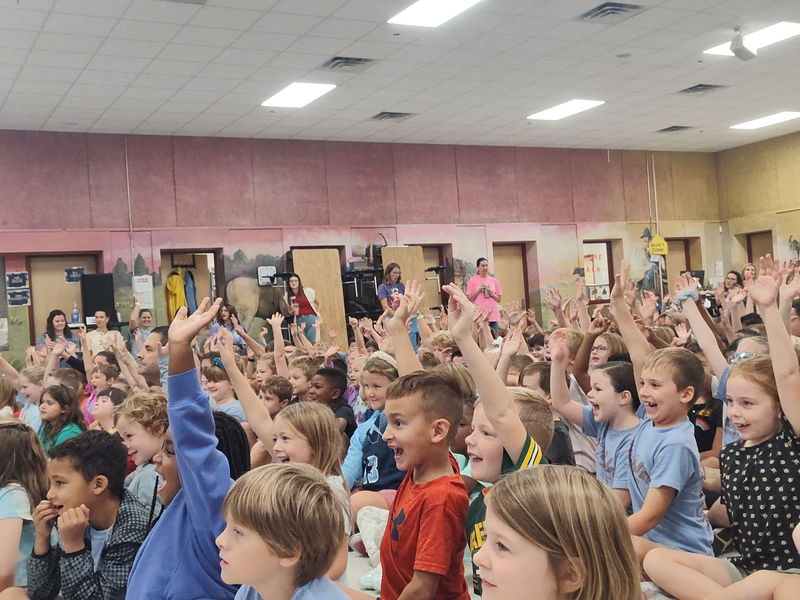 kids raising hands at author assembly