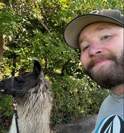 man taking a selfie with a white llama