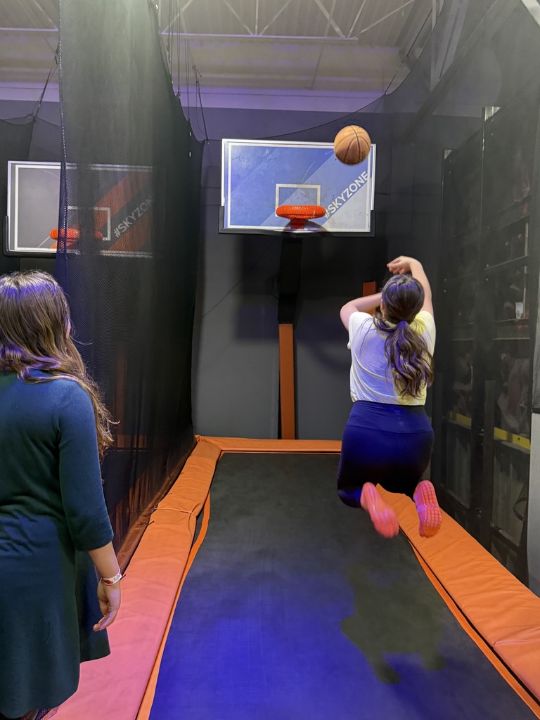 student jumping and trying to make a basket, student watching