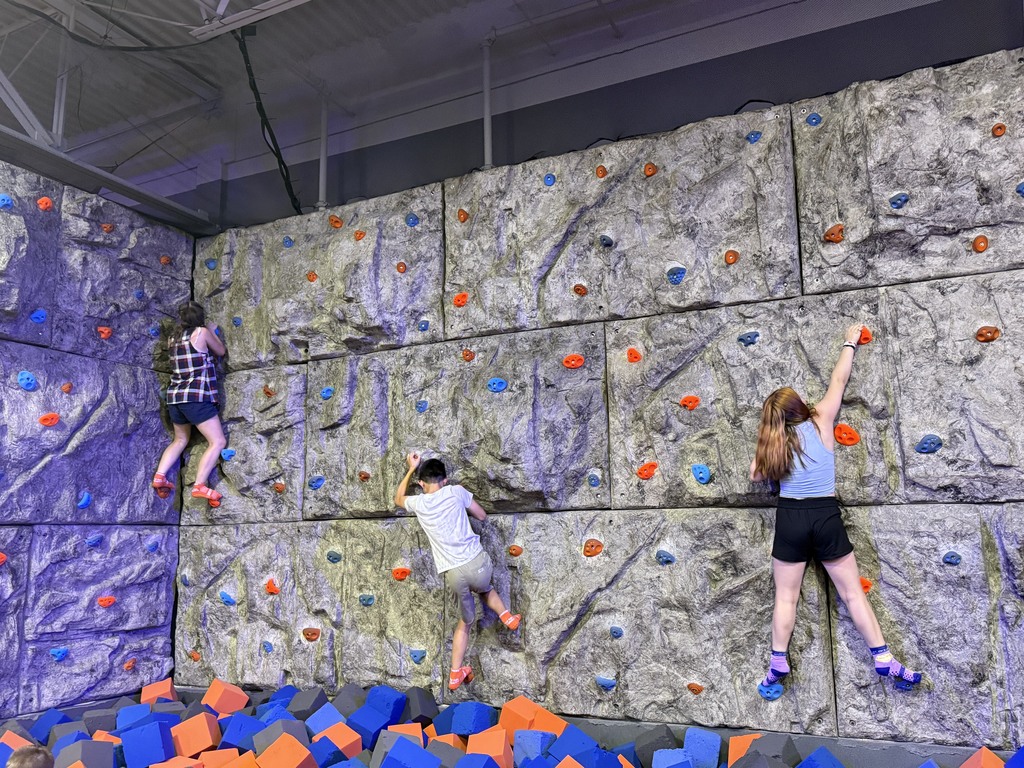 three student rock climbing