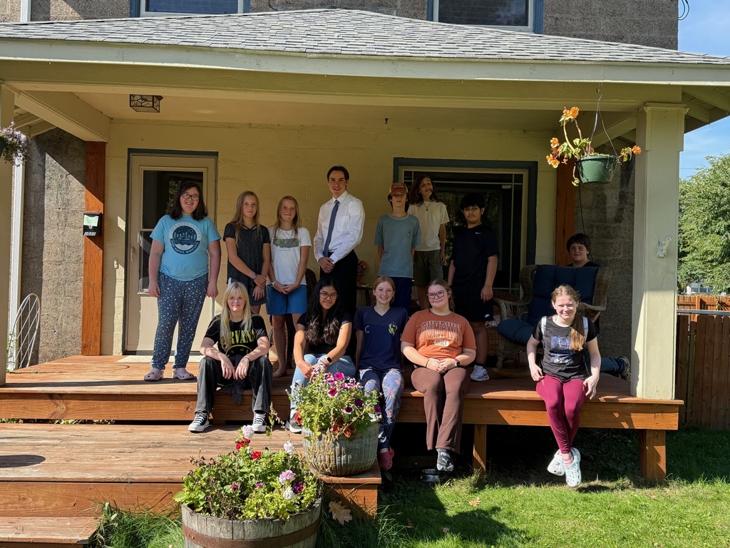 Group photo of 13 students on a porch