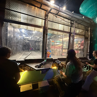 students playing a ball launching game in front of windows