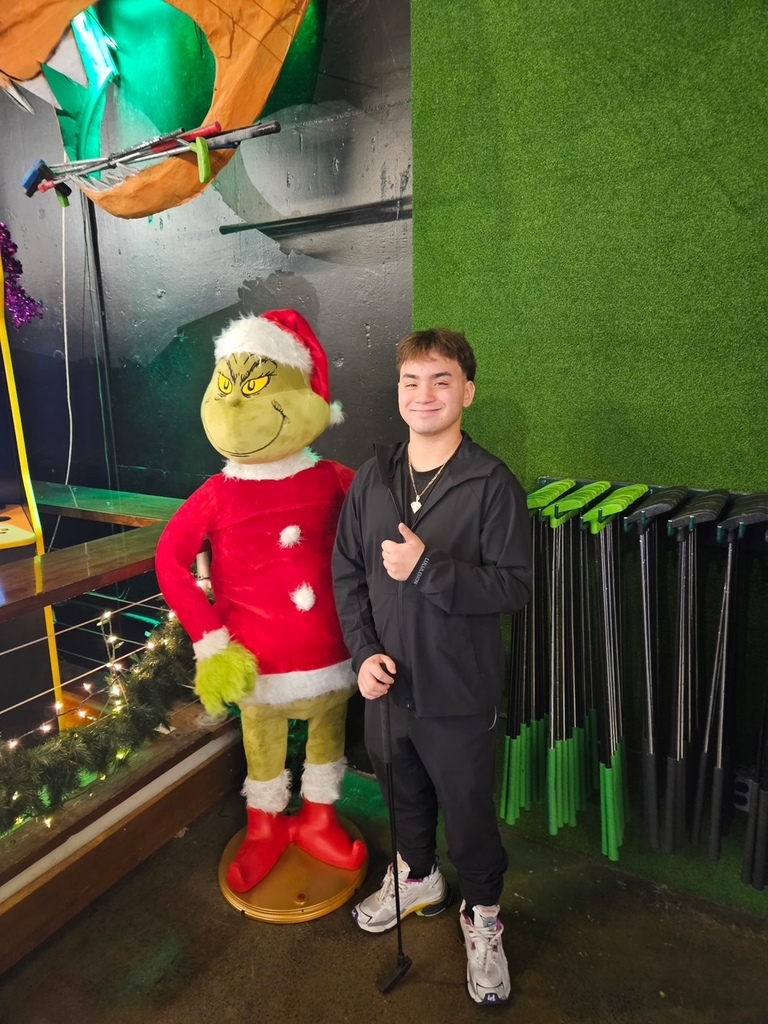 student next to the grinch character
