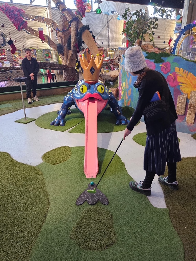two student mini golfing into a frogs mouth