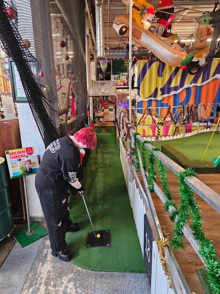 student mini golfing, background is crowded with 