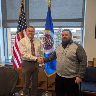two people shaking hands in front of two flags