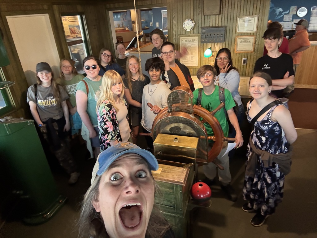 students in front of ship wheel