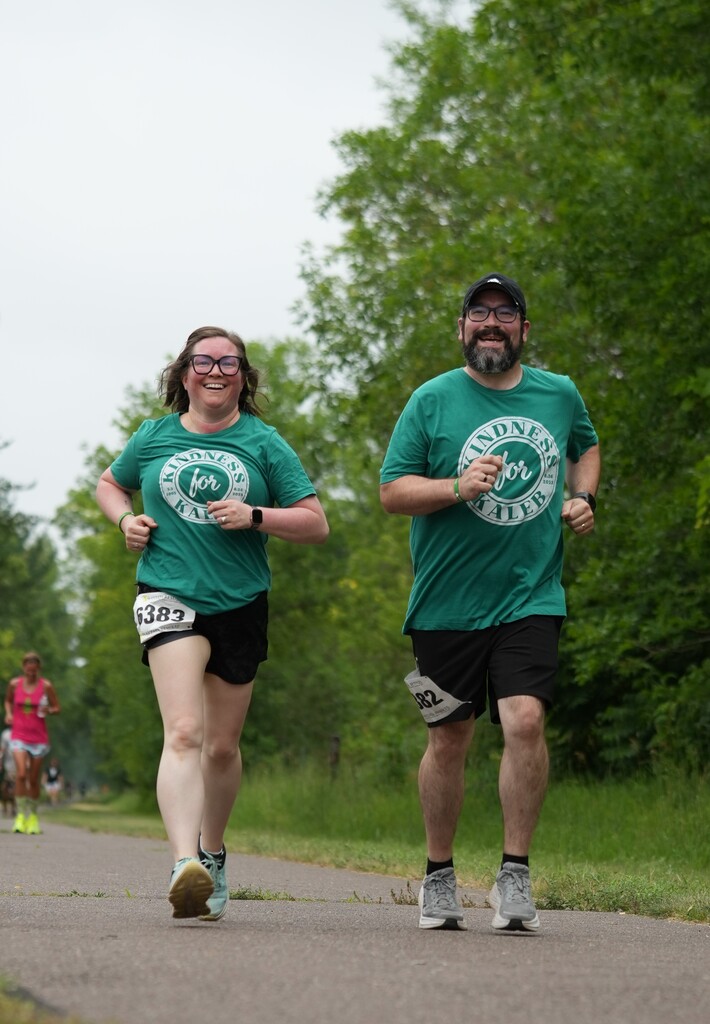 two people running a race in green shirts