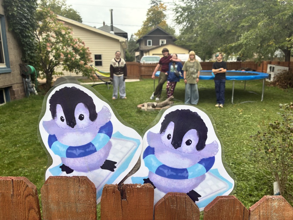 two penguin mascots and students in the background