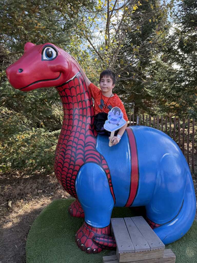 student on a spiderman painted dinosaur