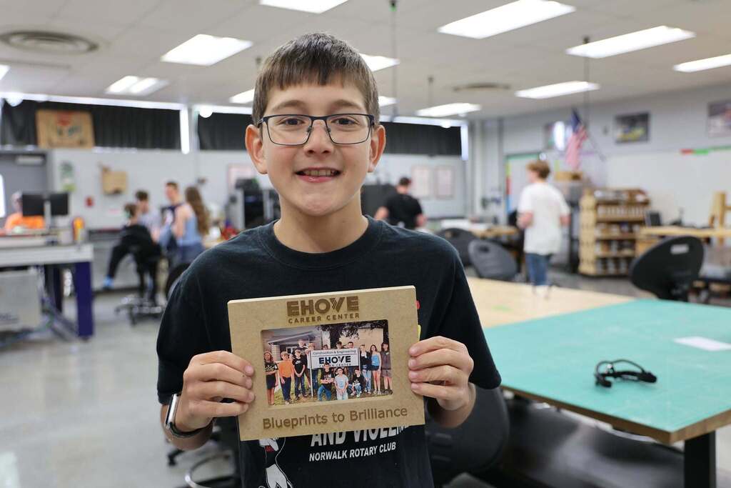 boy holding up engraved wood photo frame that says EHOVE Blueprints to Brilliance