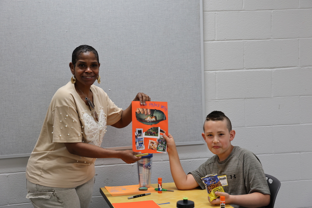 Teacher and boy holding up his art project