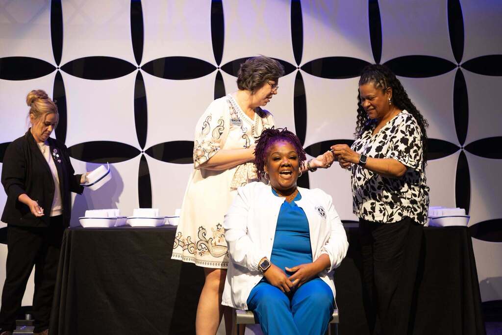 smiling nursing student seated with three staff in background
