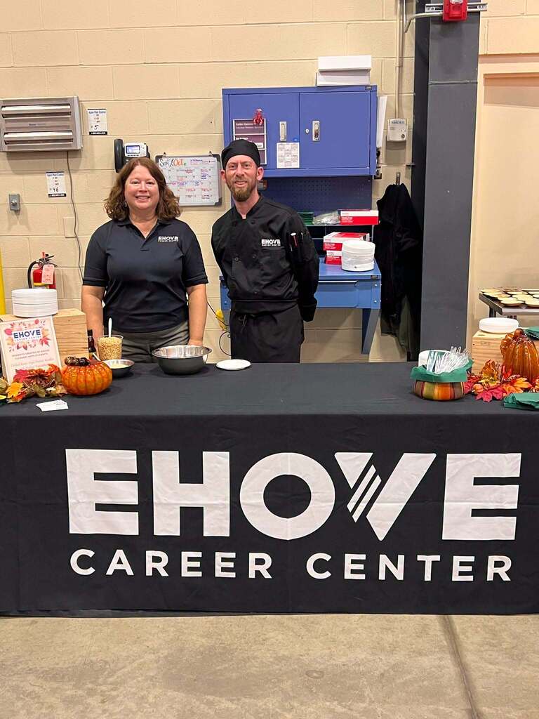 Two staff members smiling behind table with EHOVE Career Center logo