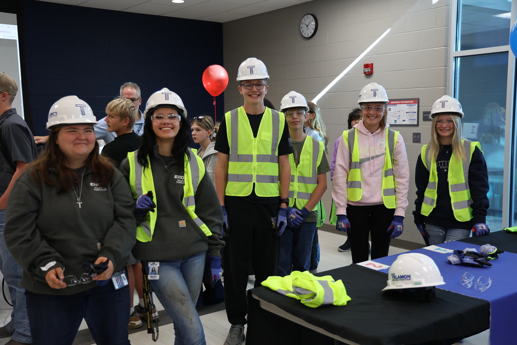 six students wearing construction gear and hard hats