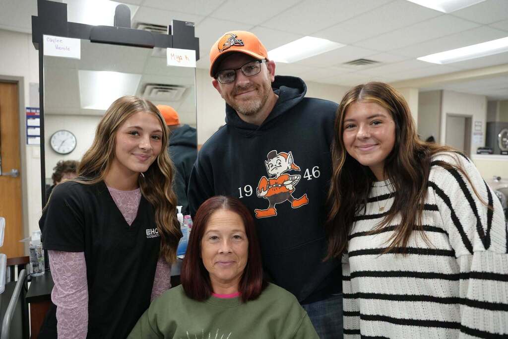Student with three family members by a mirror in the cosmetology lab
