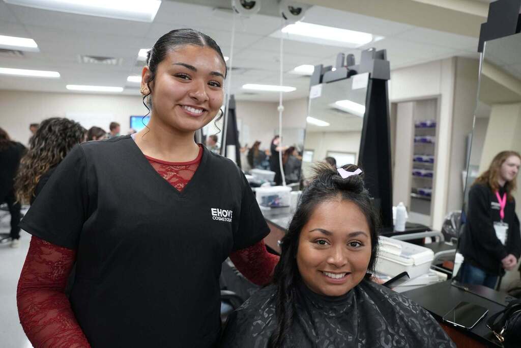 Student and seated mom smiling in the cosmetology lab