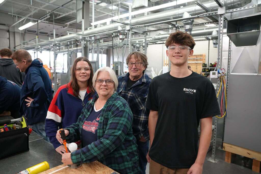 Student with his three family members by a workbench