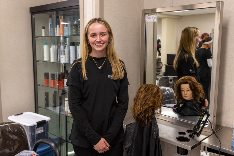 standing student near her hair styling workstation