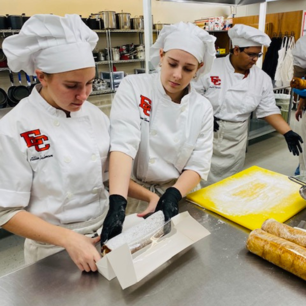 student placing a pumkin roll in a white box