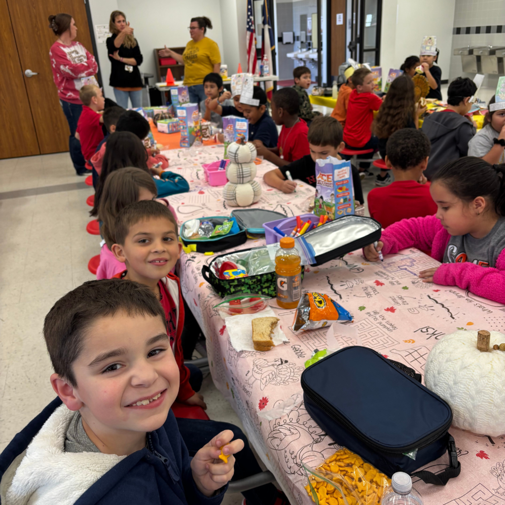 kids at cafeteria table working on activites and eating lunch