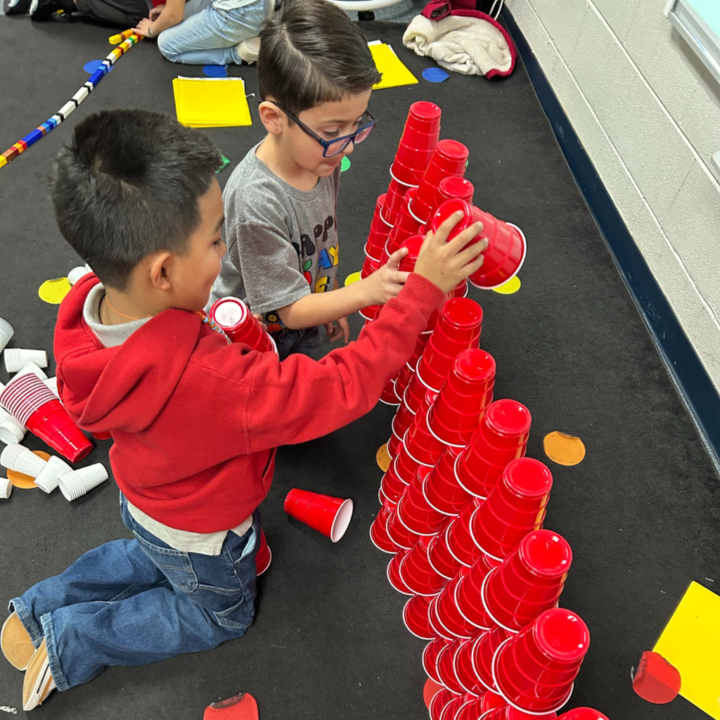 two children playing with red cups in a classroom