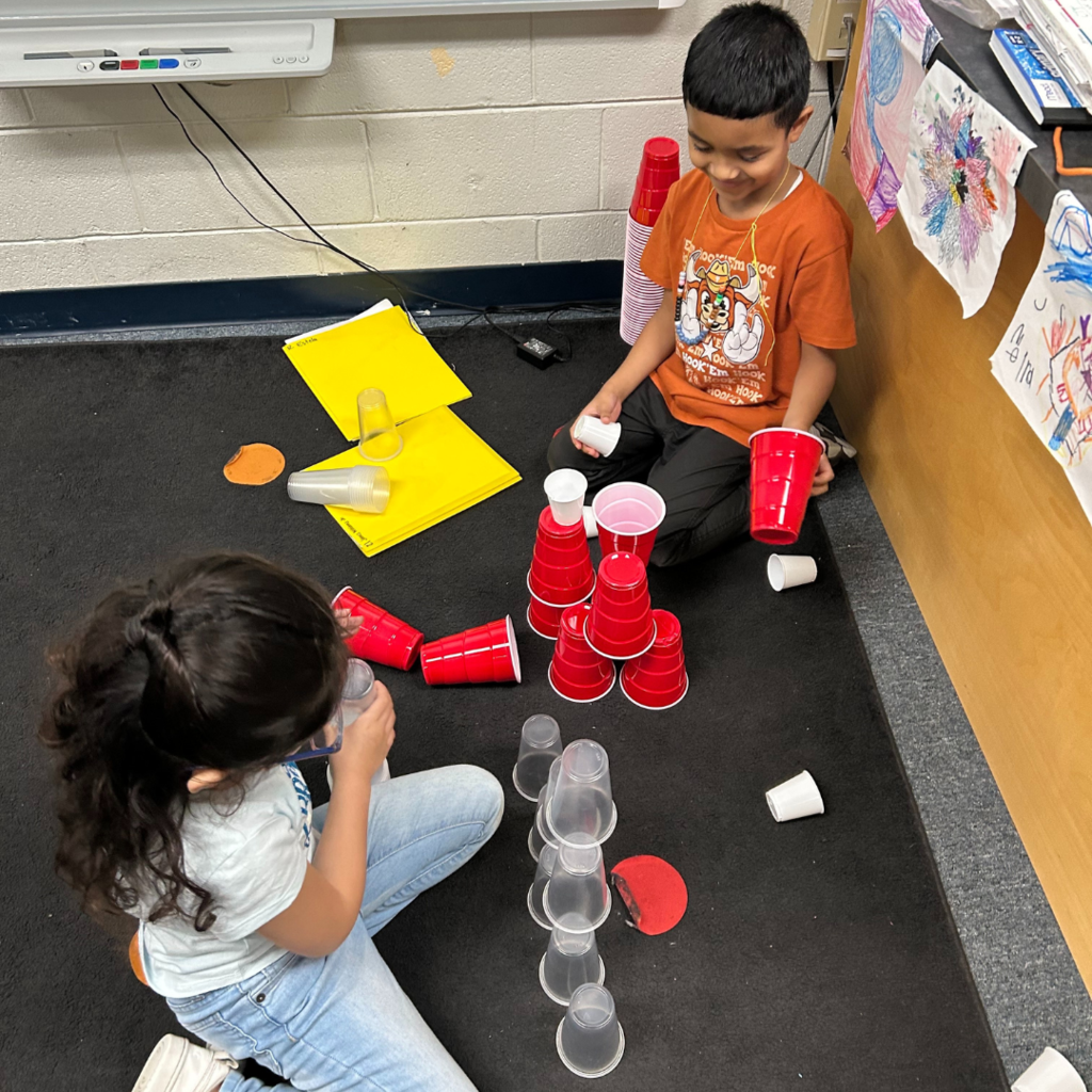 two children playing with cups in a classroom