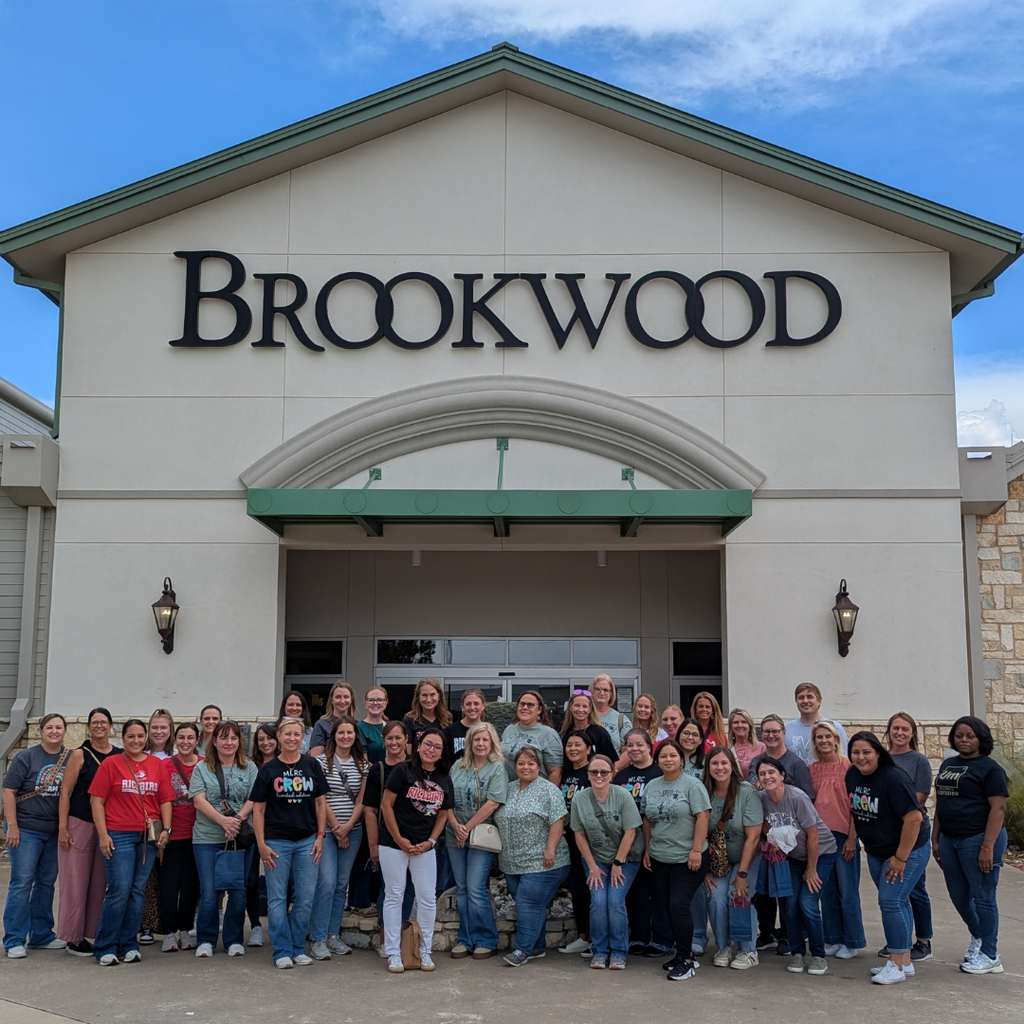 group of adults by the brookwood sign