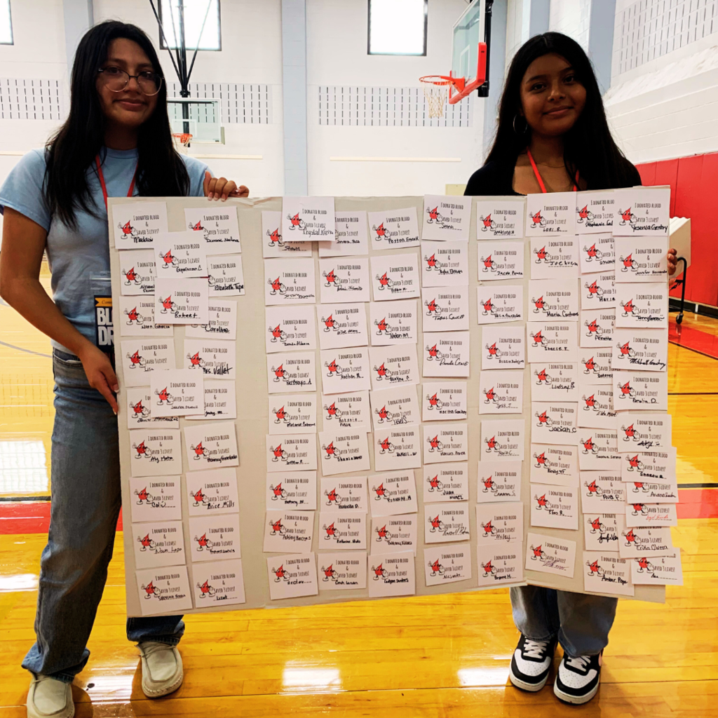 student volunteers holding sign of all the names who donated