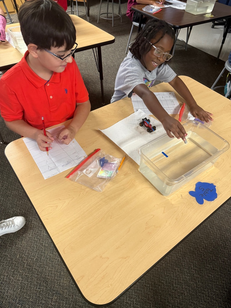 kids observing and taking notes about objects in container of water