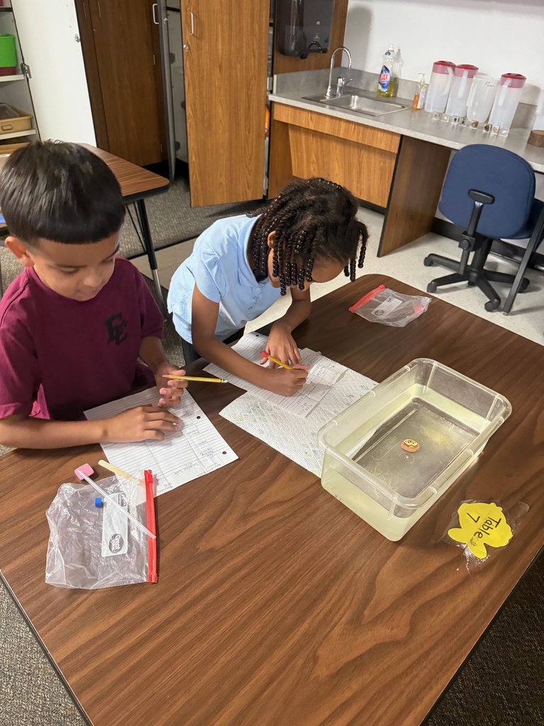 kids observing and taking notes about objects in container of water