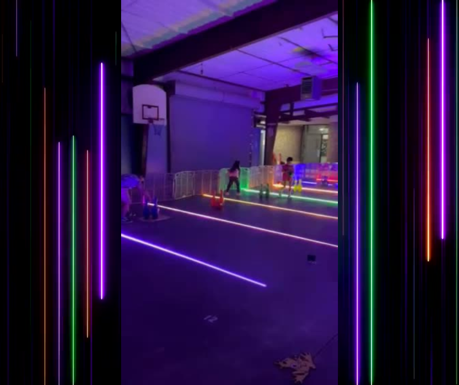 gym lit with black light and neon lights lining the bowling lane