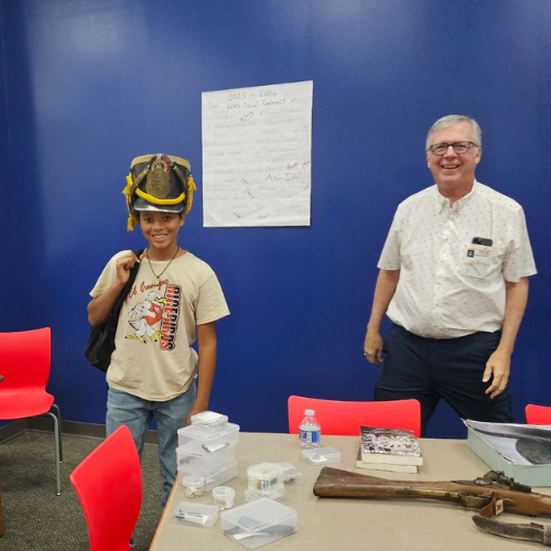 Dimmick with students trying on an artifact