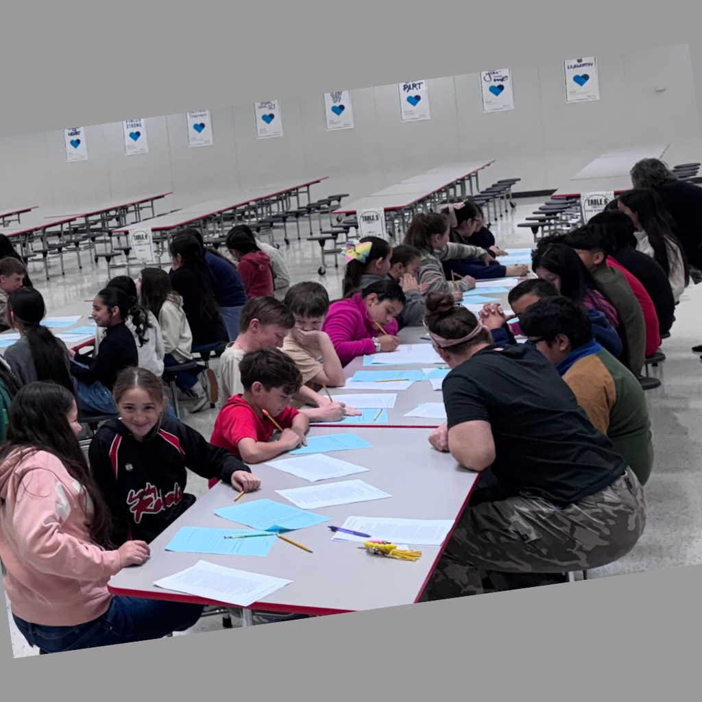 A group of 5th-grade students at Northside Elementary sit at long tables in the cafeteria, focused on a writing workshop. A teacher stands among them, guiding the lesson as students look at their papers and interact.