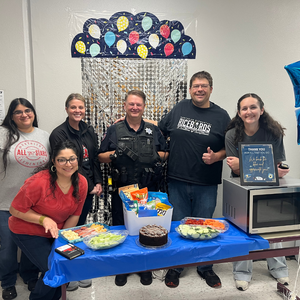 officer Lee surrounded by 5 Northside staff members and a table full of sweets and a fruit and veggie tray