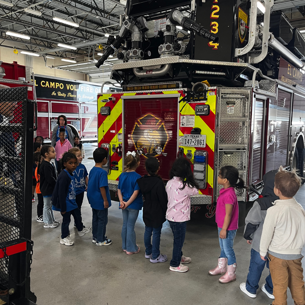 kids lined up looking at the back end of the fire truck