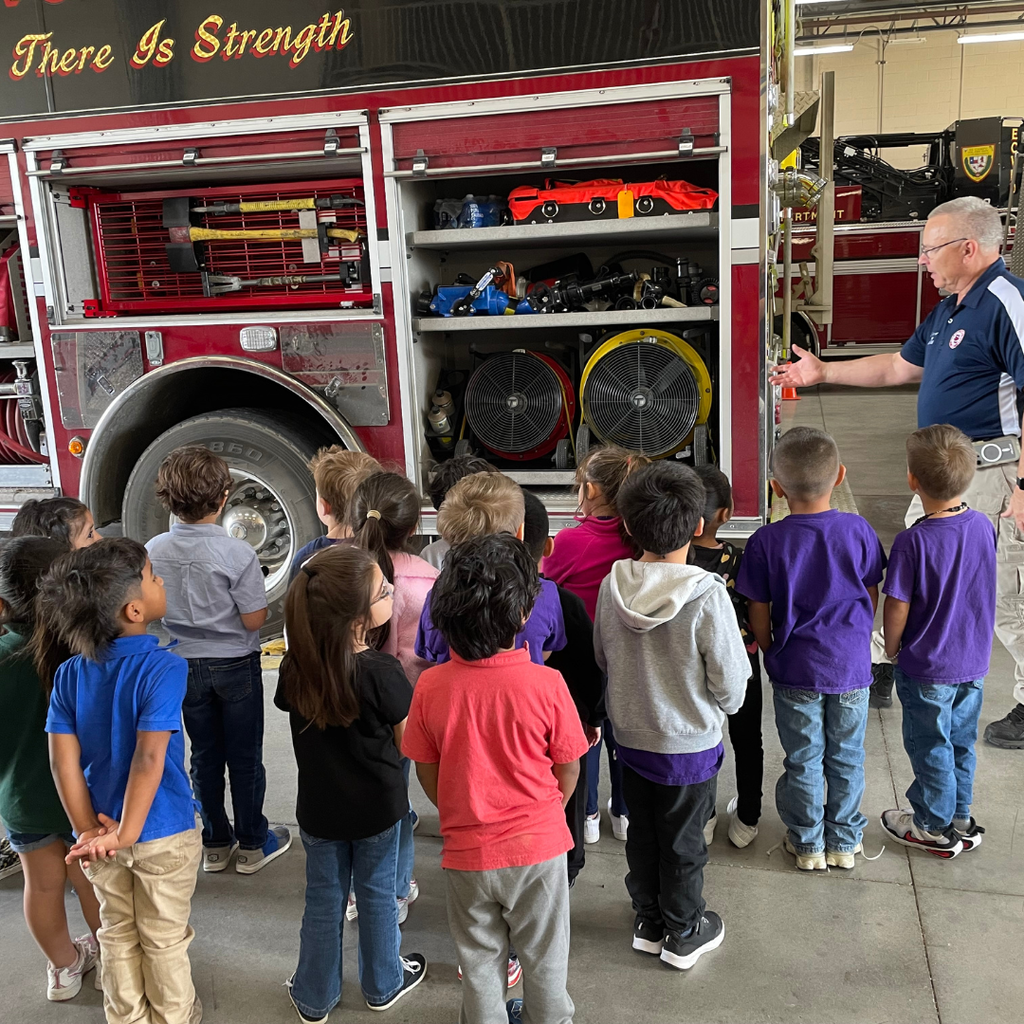 kids looking in compartment with fans and other equipment on firetruck