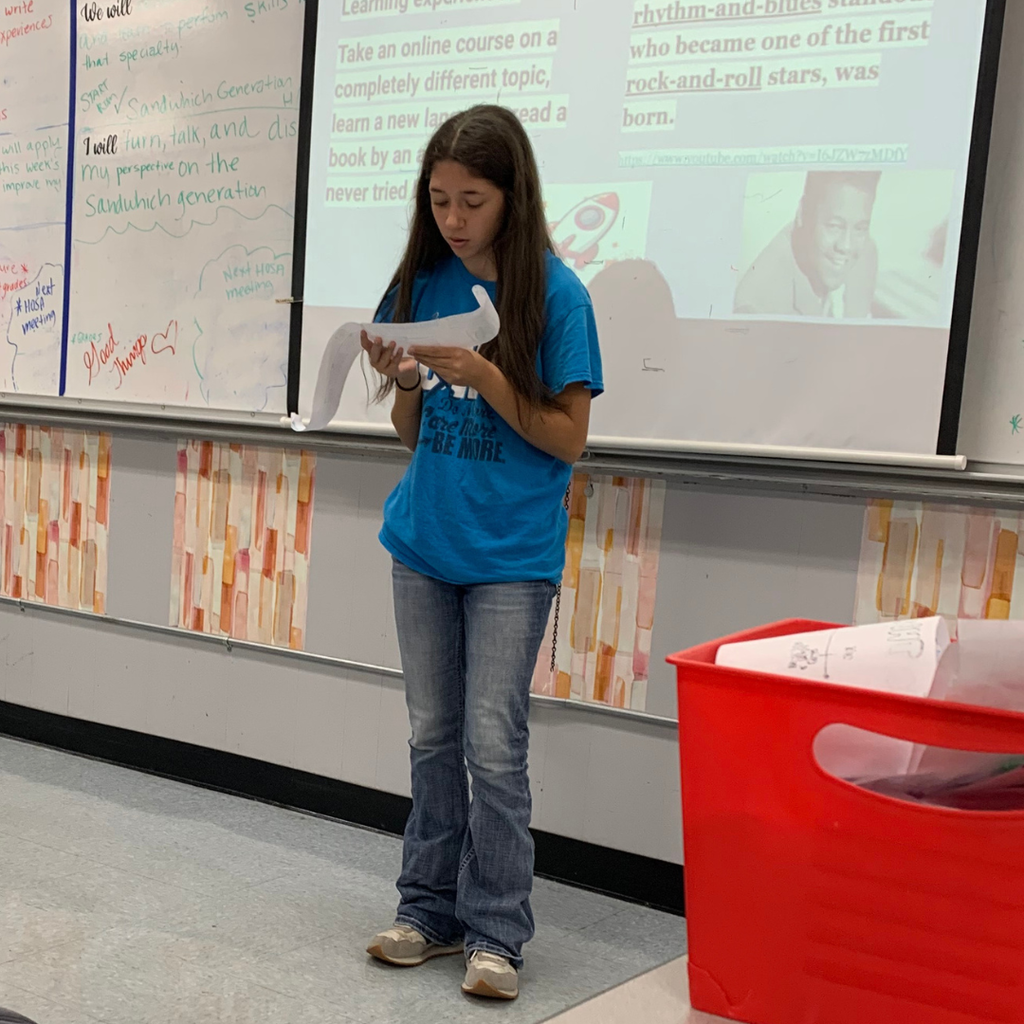 student presenting her scroll to the class