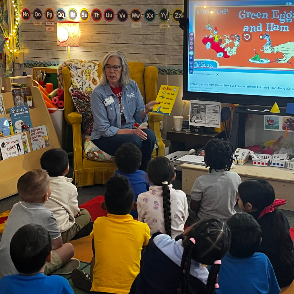 adult woman reading to students in classroom