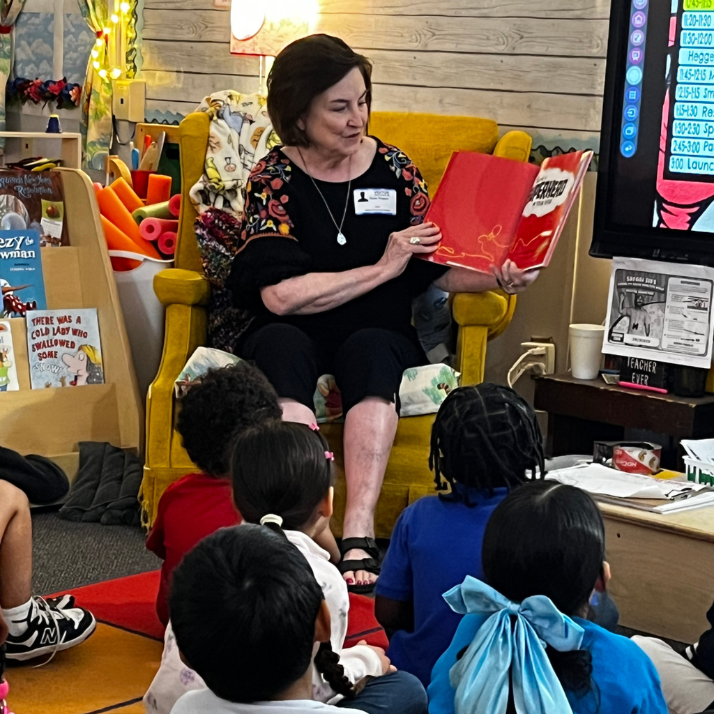 adult woman reading to students in classroom