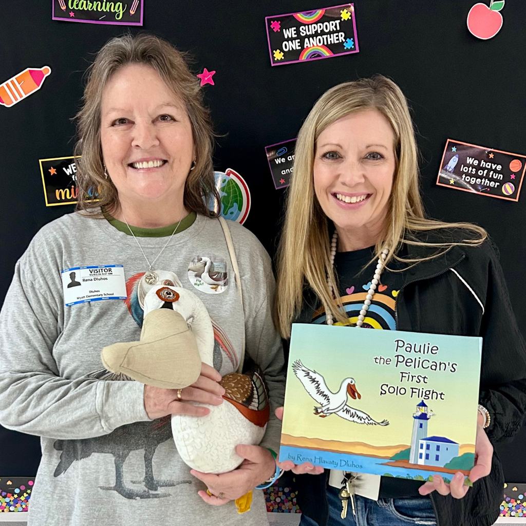 author Dluhos holding a stuffed pelican by teacher holding book