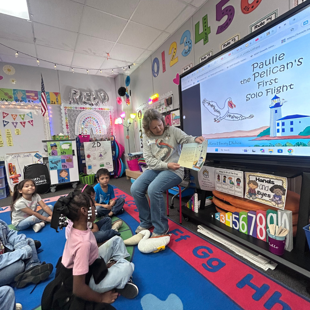 author reading book to classroom of kids sitting on the floor