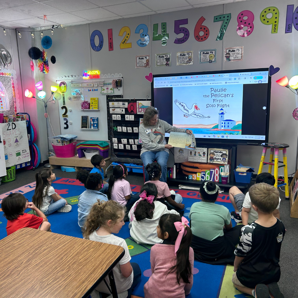 author reading book to classroom of kids sitting on the floor