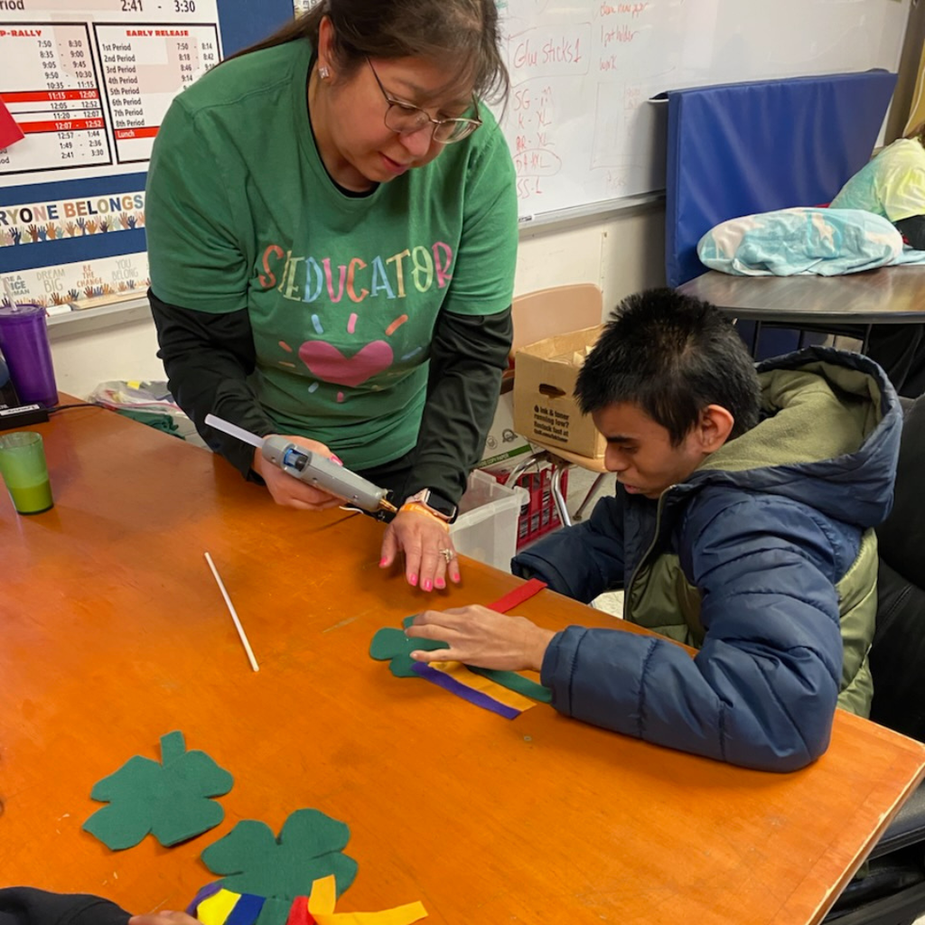 teacher helping glue on streamers with student